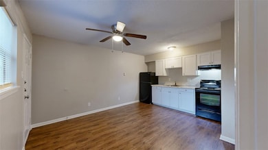 Kitchen featuring black appliances, white cabinets, light countertops, dark wood-style flooring, and a ceiling fan