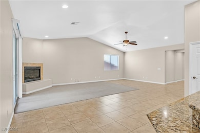 Unfurnished living room featuring light tile patterned flooring, light carpet, vaulted ceiling, recessed lighting, and a fireplace