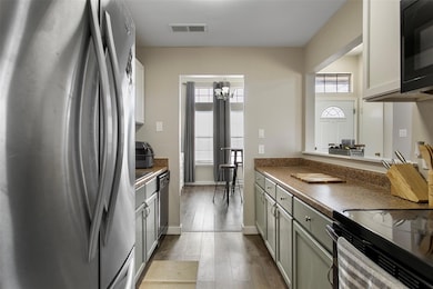 Kitchen featuring gray cabinets, black appliances, and light hardwood / wood-style floors