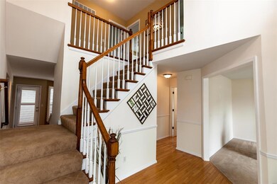 2 story entry foyer features hardwood flooring and t staircase.