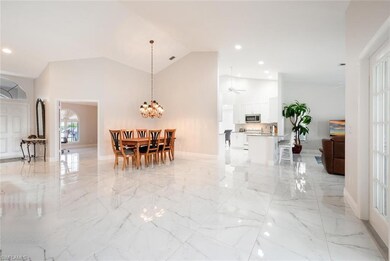 Dining area featuring light marble finish flooring, high vaulted ceiling, a chandelier, baseboards, and recessed lighting