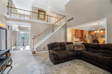 Living area with a high ceiling, crown molding, stairs, a chandelier, and light colored carpet