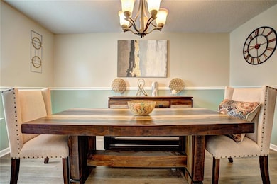 Dining area with a chandelier, wood finished floors, and a textured ceiling