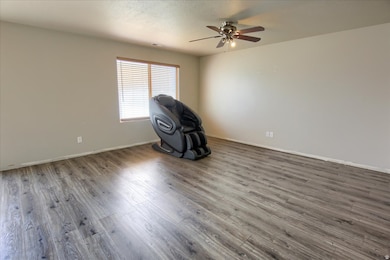 Living room featuring wood-style finished floors, a textured ceiling, and a ceiling fan