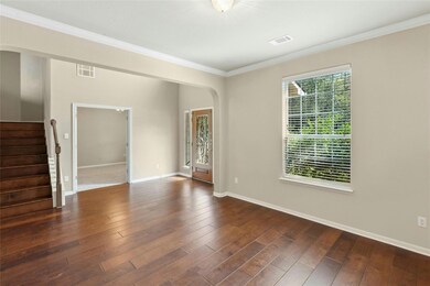 Empty room featuring ornamental molding, arched walkways, stairs, dark wood-style flooring, and baseboards