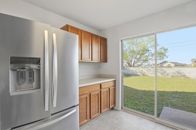 Kitchen featuring stainless steel refrigerator with ice dispenser, brown cabinets, light countertops, and light tile patterned flooring