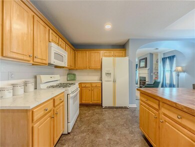 Kitchen with white appliances, arched walkways, and backsplash