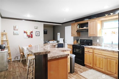 Bright and welcoming kitchen with knotty pine cabinetry, black appliances, and plenty of counter space, plus room for a dining table to enjoy everyday meals.