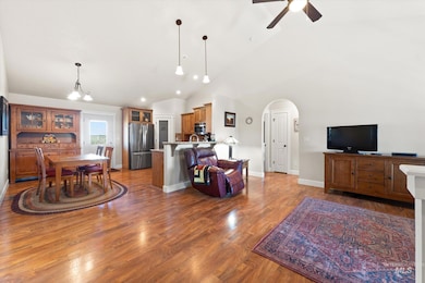 Living room with lofted ceiling, arched walkways, a ceiling fan, and wood finished floors