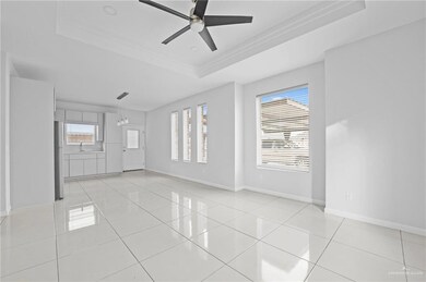 Tiled spare room with ceiling fan, plenty of natural light, sink, and a tray ceiling