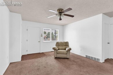 Sitting room with a textured ceiling, carpet, and a ceiling fan