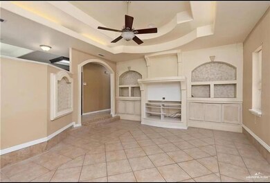Unfurnished living room with a raised ceiling, arched walkways, a ceiling fan, and built in features