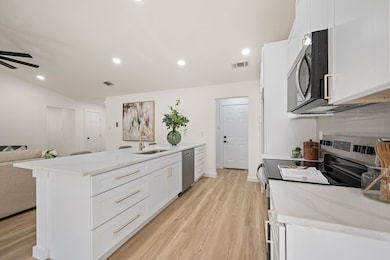 Kitchen featuring stainless steel appliances, light stone counters, white cabinetry, light wood-type flooring, and recessed lighting