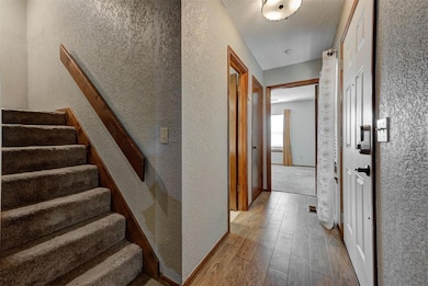Stairs featuring wood finished floors, a textured wall, and baseboards