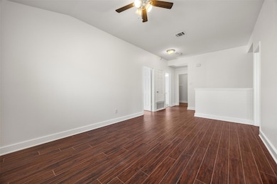 Spare room with dark wood-style flooring, a ceiling fan, and vaulted ceiling
