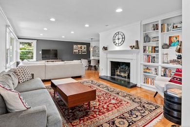 Bright and sunny living room with bookshelves, hardwood floors, gas fireplace and remote control blinds