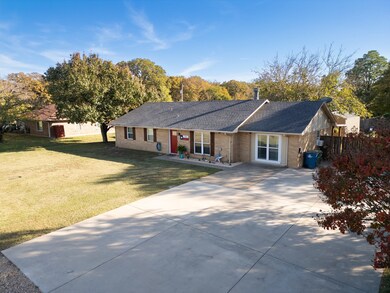 Single story home with a shingled roof, brick siding, driveway, and a porch