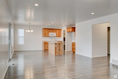 Unfurnished living room featuring light wood-style floors, a chandelier, and recessed lighting