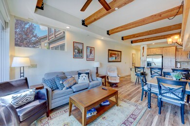 Living room with beamed ceiling, light wood-style floors, and recessed lighting