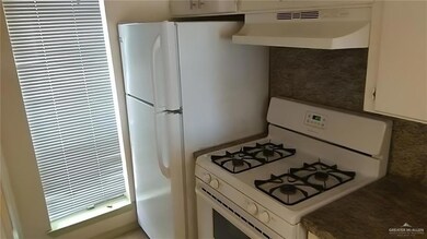 Kitchen featuring under cabinet range hood, white cabinets, and white gas range