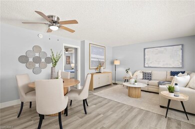 Living area featuring a textured ceiling, light wood-style floors, a ceiling fan, and baseboards