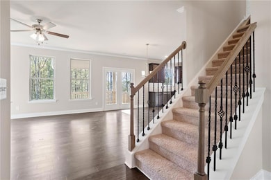 Stairs with ornamental molding, wood finished floors, and ceiling fan