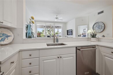 Kitchen featuring stainless steel dishwasher, white cabinets, and light stone counters