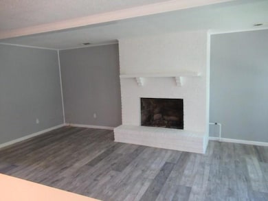 Unfurnished living room featuring wood finished floors, a fireplace, and baseboards