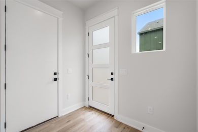 Entrance foyer with light wood-style floors and b