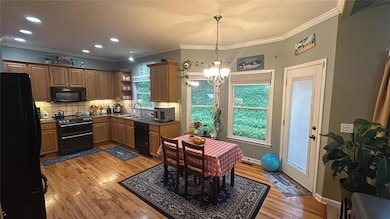 Kitchen featuring black appliances, open shelves, light wood-type flooring, a chandelier, and decorative backsplash