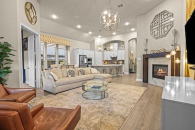 Living area with a tiled fireplace, a chandelier, recessed lighting, light wood-style floors, and lofted ceiling