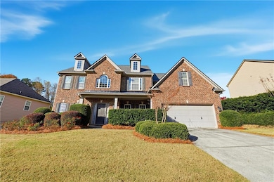 View of front of house featuring brick siding, driveway, covered porch, a front lawn, and a garage