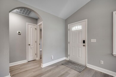 Foyer with vaulted ceiling and light wood-type flo