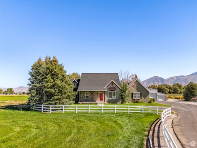 View of front of house featuring a mountain view, a detached garage, stone siding, and a view of countryside