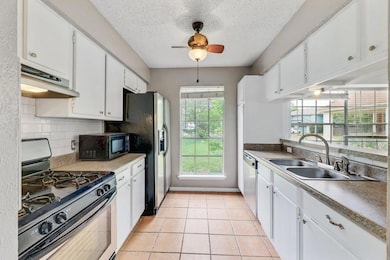 Kitchen with stainless steel gas range oven, light countertops, white cabinets, and black microwave