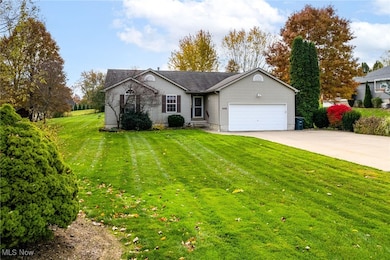 Ranch-style home with concrete driveway, a front lawn, and an attached garage