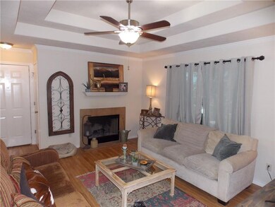 Living room featuring a raised ceiling, ceiling fan, crown molding, and light hardwood / wood-style floors