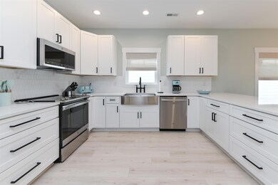 Kitchen with white cabinetry, light hardwood / woo
