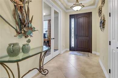 Foyer with ornamental molding, french doors, and light tile patterned floors