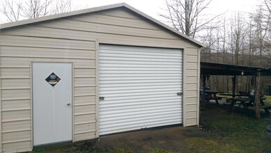 Metal garage with roll-up door, concrete floor, power, attached lean-to shed