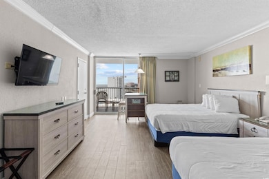 Bedroom featuring a wall of windows, access to outside, light wood-type flooring, a textured ceiling, and ornamental molding