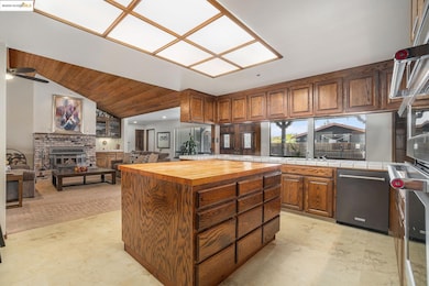 Kitchen featuring butcher block countertops, a center island, appliances with stainless steel finishes, open floor plan, and lofted ceiling