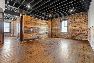 Unfurnished living room with brick wall and hardwood / wood-style floors