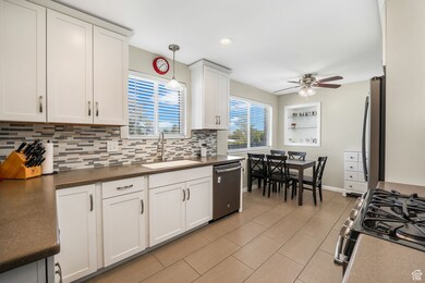 Kitchen featuring dark countertops, stainless steel appliances, white cabinetry, decorative backsplash, and recessed lighting