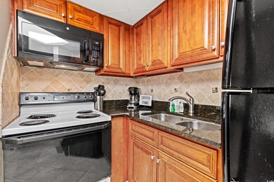 Kitchen featuring brown cabinetry, backsplash, black appliances, and a sink