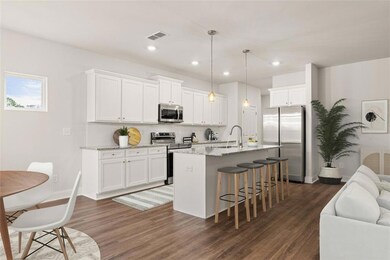 Kitchen with white cabinetry, light stone counters