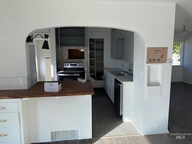 Kitchen featuring appliances with stainless steel finishes, white cabinets, arched walkways, and wood counters