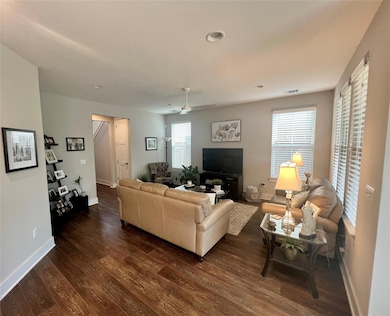 Living room with dark wood-style floors, baseboar