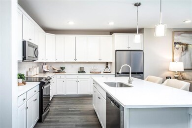Kitchen with stainless steel appliances, a sink, light countertops, dark wood-style flooring, and white cabinetry