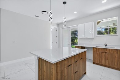 Kitchen featuring brown cabinets, modern cabinets, a kitchen island, light marble finish flooring, and pendant lighting